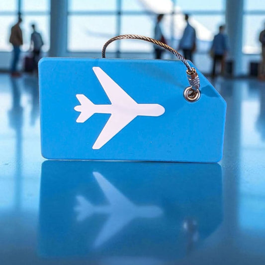 Blue luggage tag with airplane icon on a reflective floor with blurred people in the background